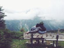 Loving Couple Sitting on a Bench Looking at the Mountains